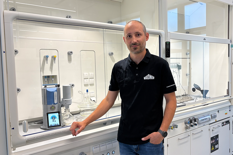 Moriz Walter, Head of Product Development of WALDNER Lab Space Solutions, is standing in front of a laboratory fume hood with a LADS-enabled PC 3001 VARIO select vacuum pump from VACUUBRAND.